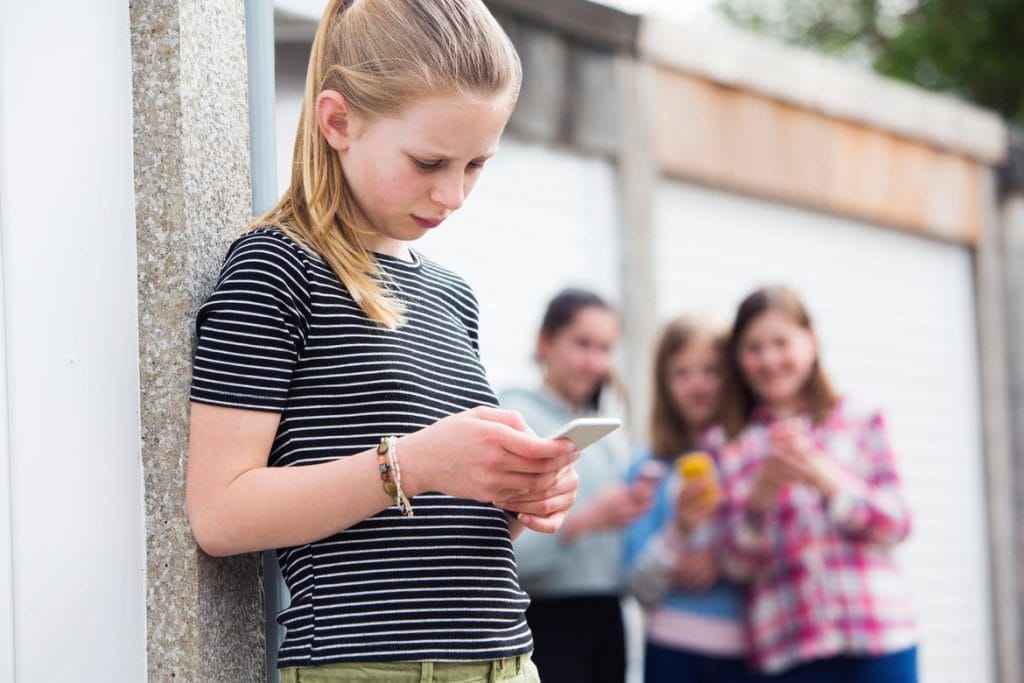 tween on phone other kids in background How to help your child transition to a new school