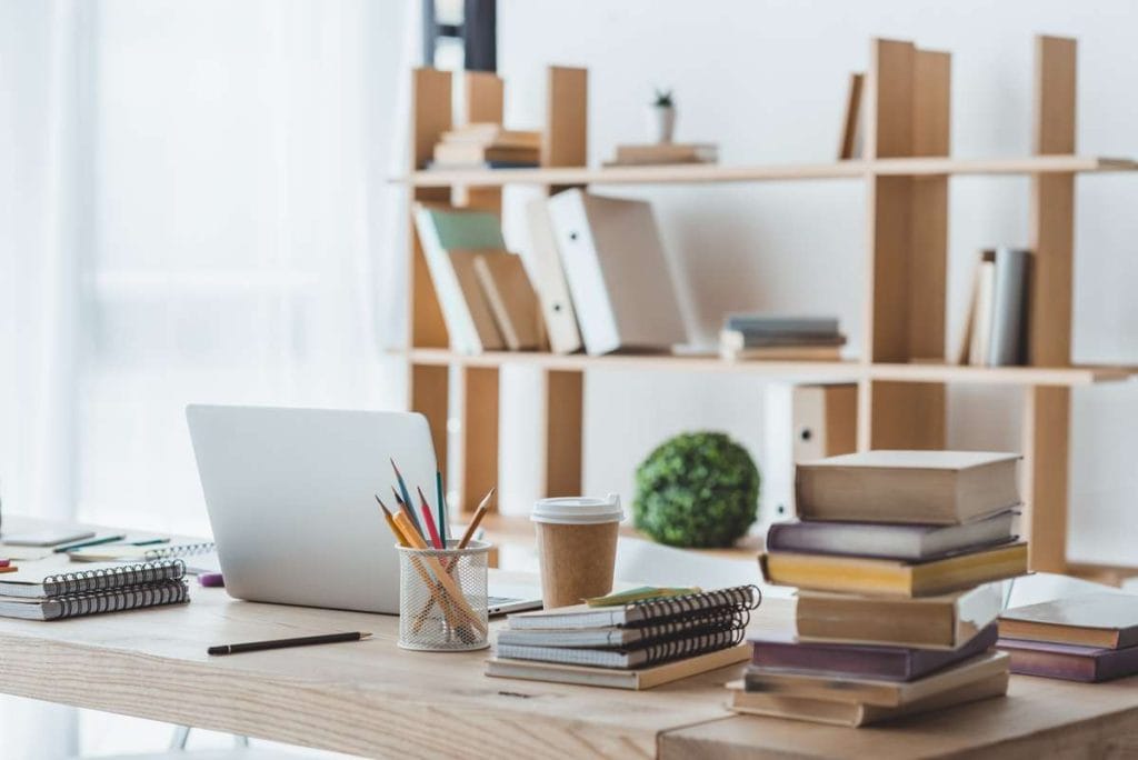 Home office desk with laptop pens coffee books and bookcase